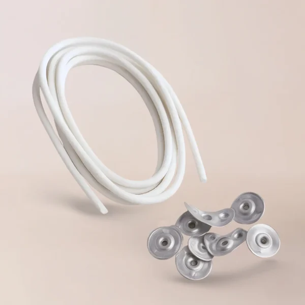 Un cordón Pabilo Importado blanco enrollado y un montón disperso de botones o broches de metal, insumos perfectos para velas, descansan sobre un fondo neutro.
