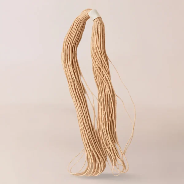Un paquete de Pabilo Nacional, fideos largos crudos de color beige atados con una banda blanca, se encuentra sobre un fondo claro y liso, parecido a los insumos para velas que suelen usar los fabricantes de velas en su artesanía.