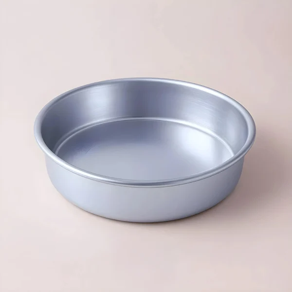 La Base Pebetero, un molde para hornear redondo de metal plateado con lados lisos, reposa sobre una superficie de color beige claro, ideal para proyectos de manualidades o como accesorio de fabricantes de velas en Colombia.