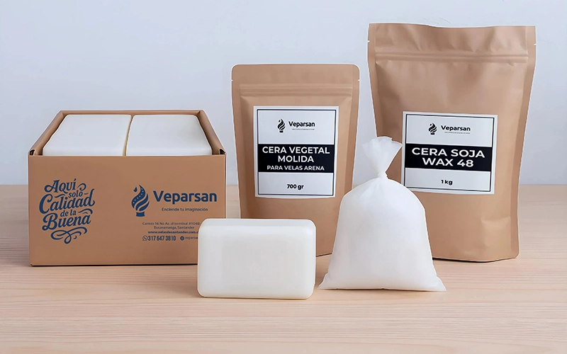 Varios paquetes de productos de cera blanca, que incluyen barras, una caja, una bolsa y bolsas resellables de fabricantes de velas, se exhiben en una superficie de madera, perfectos para insumos para velas o para crear hermosas velas al estilo colombiano.