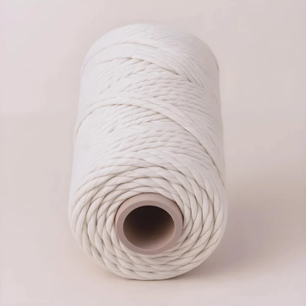 Un gran carrete de Pabilo de Máquina blanco y grueso se muestra sobre un fondo claro y liso, ideal para usar como insumo para velas.