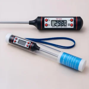 Termómetro: Paquete de dos termómetros digitales (uno muestra 29,8 °C), cada uno con un estuche protector y una correa de muñeca azul, ideal para cocinas y fabricantes de velas que necesitan un control preciso de la temperatura para cocinar o hacer velas.